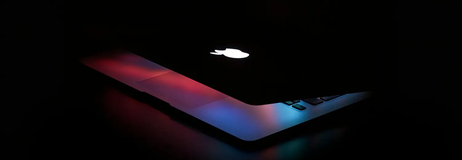 product photography of MacBook with glowing Apple logo in dark setting