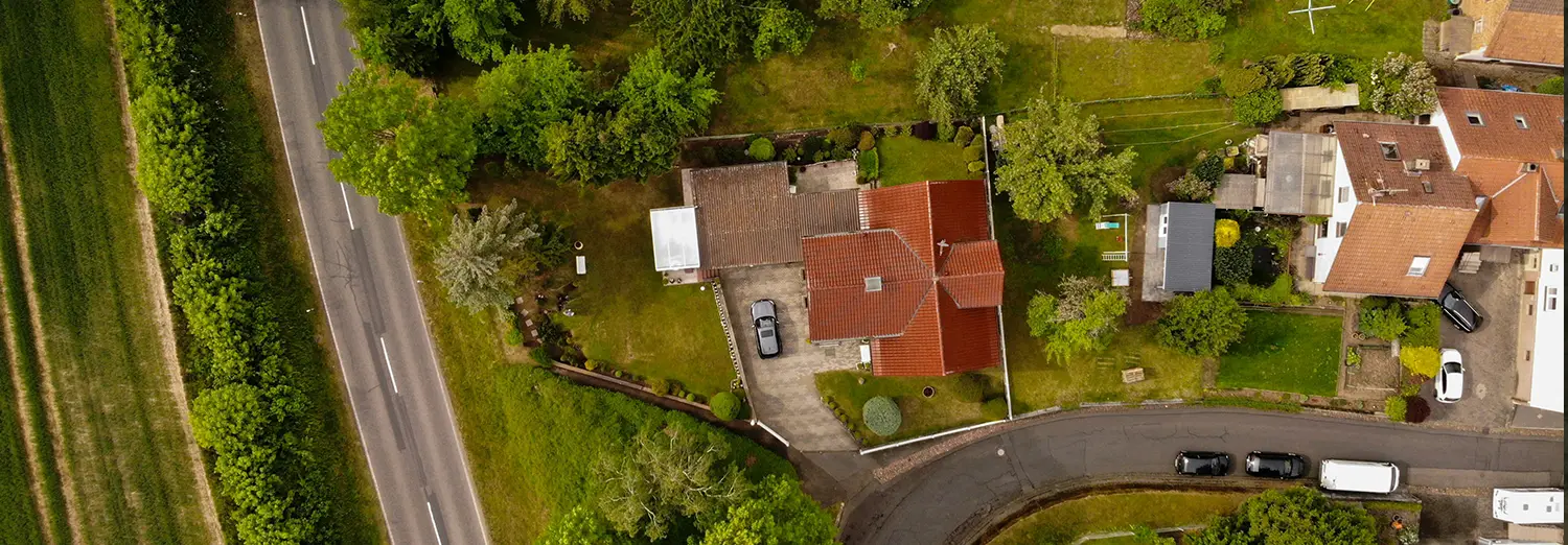 aerial drone photography of residential house with red roof and green surroundings